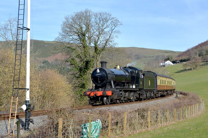 a train traveling down train tracks near a field