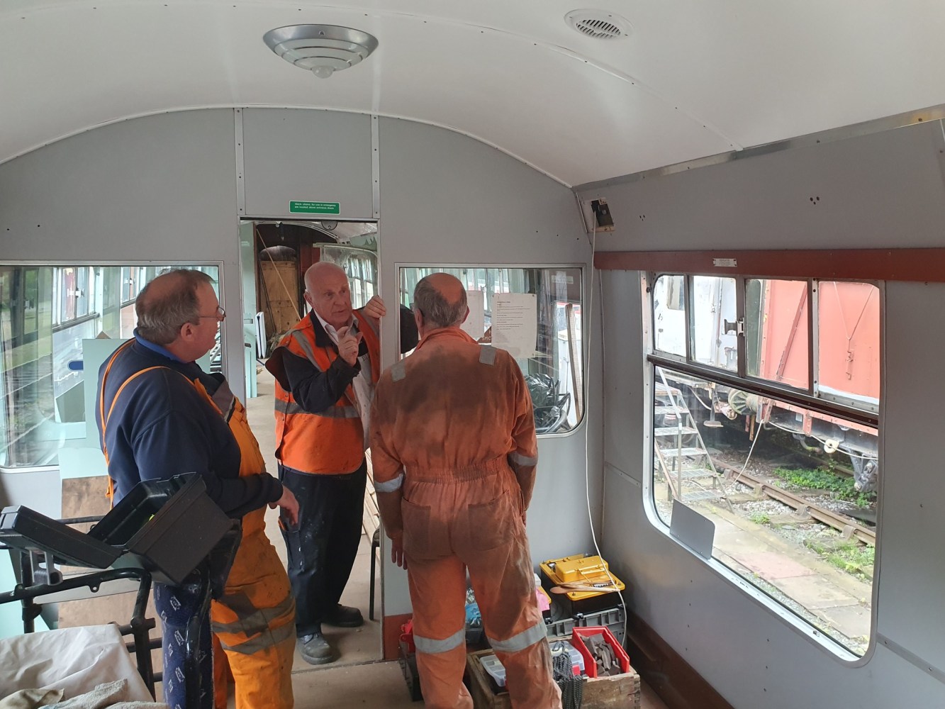 a group of volunteers discussing heritage railcar repairs whilst inside a railcar