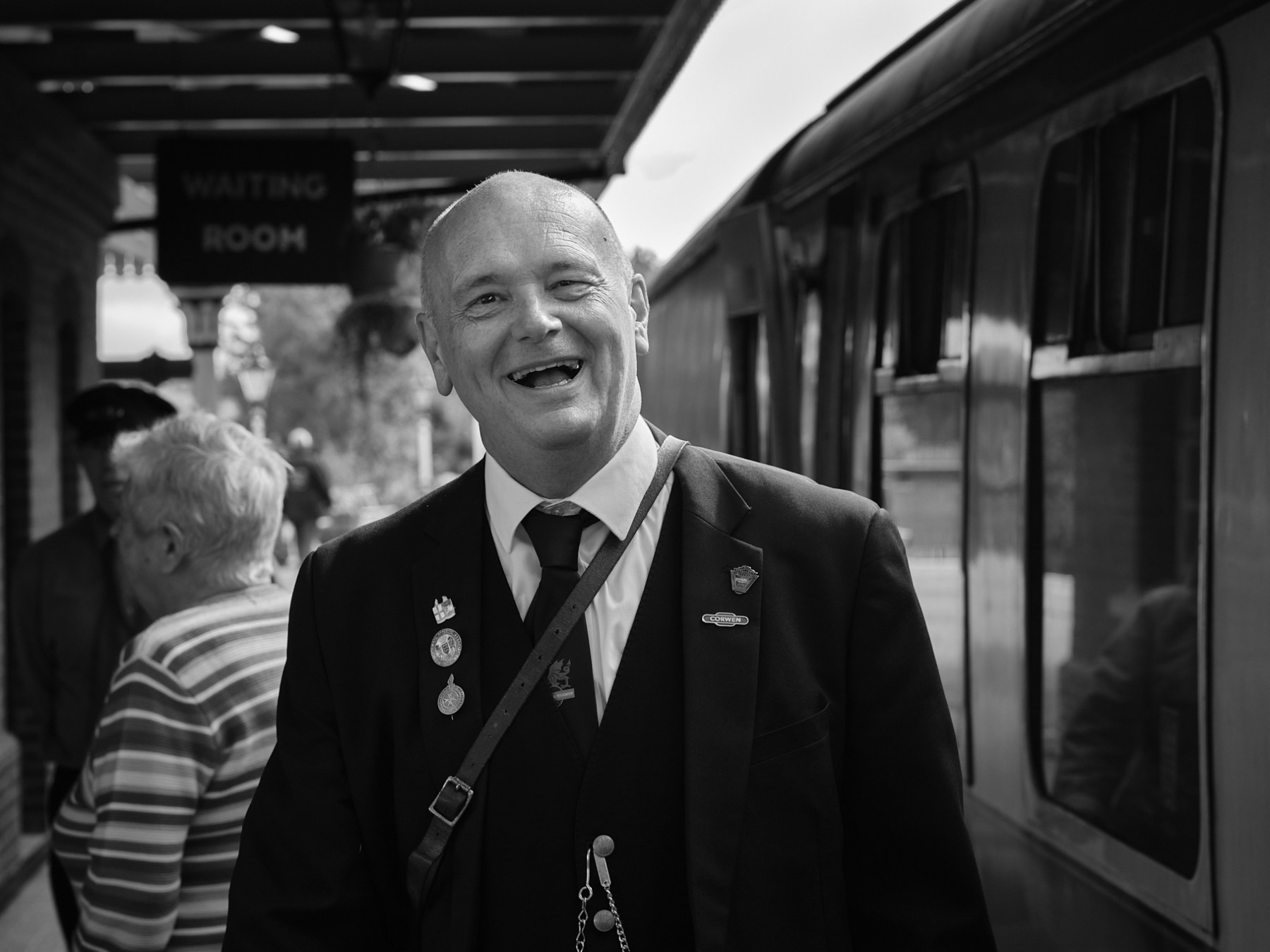 a man wearing a suit and tie standing next to a train carriage