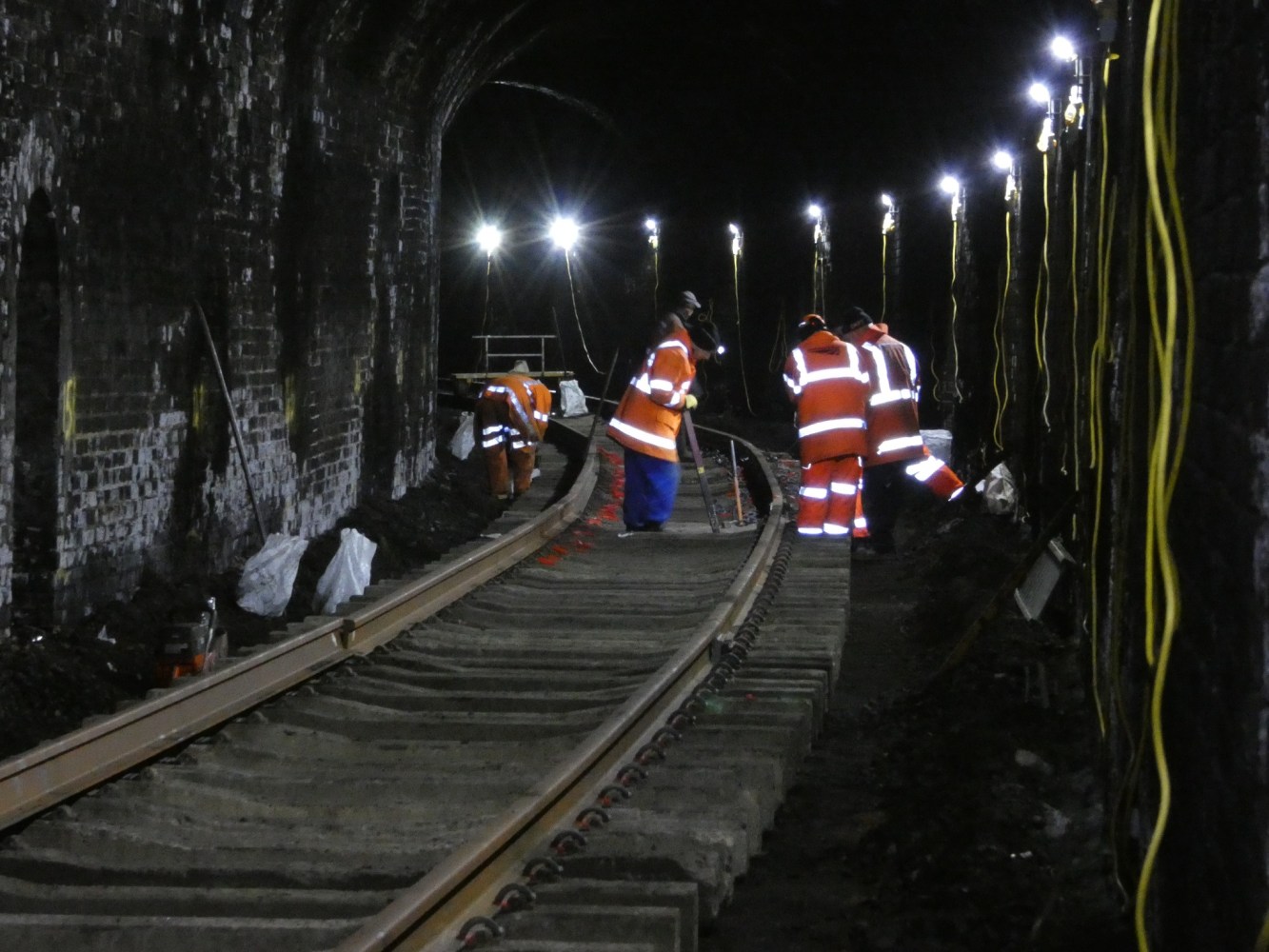 a group of people working on railway tracks inside a tunnel